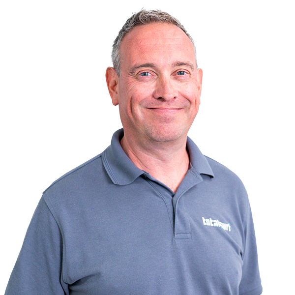 Man in a blue polo shirt standing against a plain white background, smiling at the camera.
