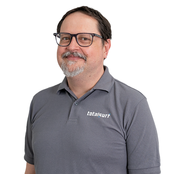 Man in glasses and a gray polo shirt with "totalsurf" logo, standing against a white background.